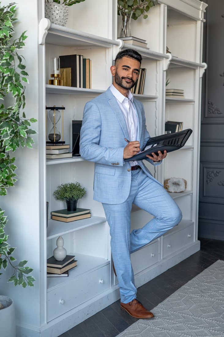 Hammad Mahmud, real estate salesperson, in a blue suit holding his client folder